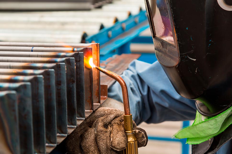 Skill worker performs gas welding on steel workpiece